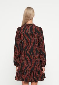 Black dress with red and orange wavy leaf pattern, long sleeves, ruffled neckline, and tiered hem. Visible back keyhole opening.