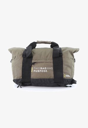 Duffle-Bag aus olivgrünem und schwarzem Stoff, mit schwarzen Trägern, einem oberen Griff und dem Text "DIESE TASCHE HAT EINEN ZWECK" sowie einem Logo.