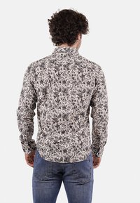 Camicia a maniche lunghe con motivo floreale in bianco e nero, realizzata in tessuto leggero con colletto a bottoni e silhouette aderente.