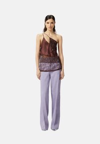 Top in raso marrone con dettagli di perline intricate e sovrapposizioni di pizzo, abbinato a pantaloni larghi in lavanda chiara, che mostrano texture morbide.