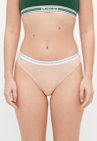 Lacoste kelnaitės silde su minkštu elastingu juosmeniu, puoštu baltu logotipu. Lygus audinys ir minimalistiškas dizainas.