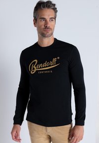 Schwarz langärmliges T-Shirt mit goldenem "Bendorff"-Logo und dem Text "CONTRASTS", aus weichem Material, figurschnittige Passform, Rundhalsausschnitt.