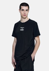 Camiseta atlética negra de manga corta con cuello acanalado y detalle sutil del logo en el pecho, fabricada con una tela suave y ligera.