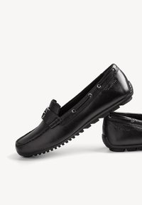 Svarta läderloafers med texturerad ovandel, dekorativ frontdetalj, slip-on design och gummisulor med greppnubber.