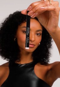 KIKO langvarig øyenbrynspenn i svart etui med rosa tupp, holdt av en hånd. Har en jevn, matt finish og elegant design.