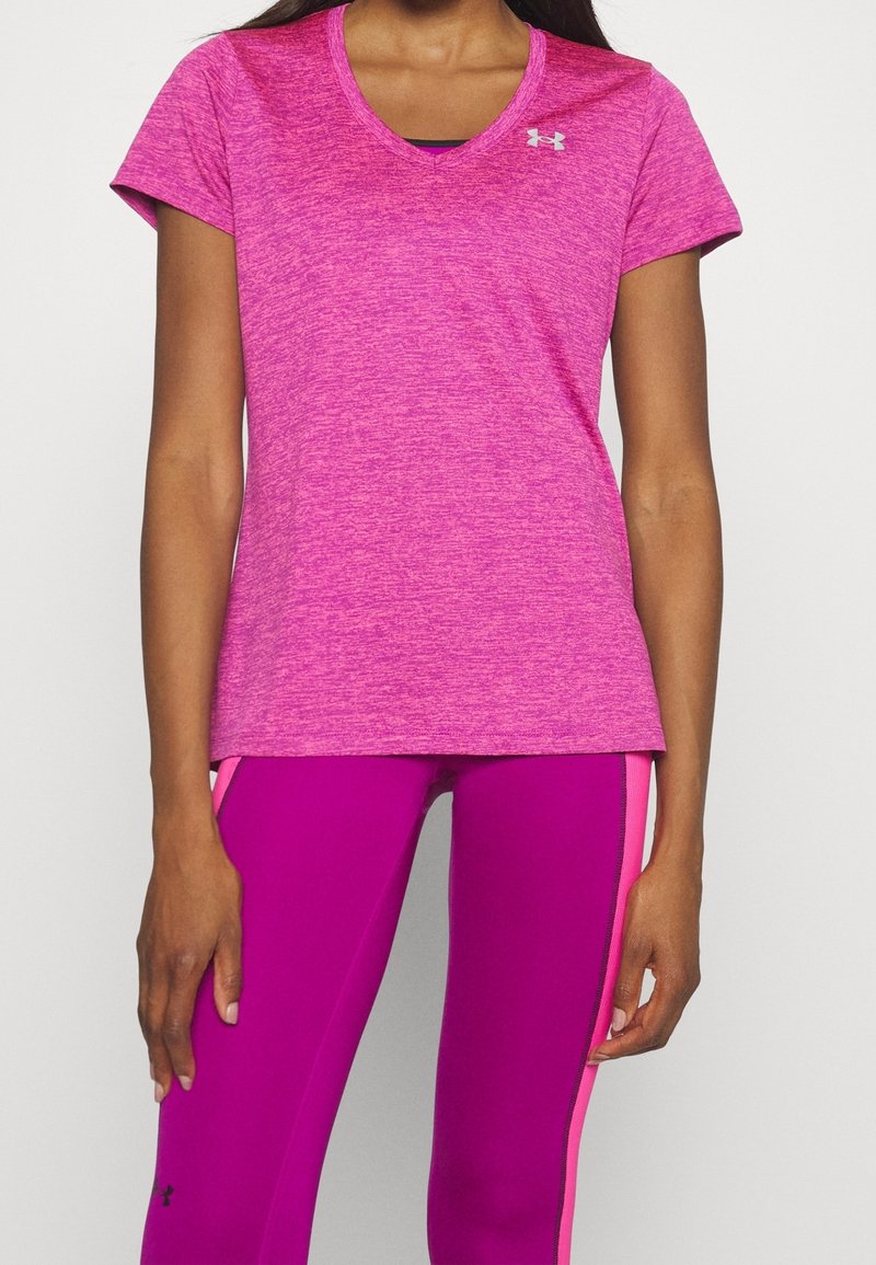 Camiseta deportiva de manga corta y escote en V en rosa brillante jaspeado, combinada con leggings ajustados rosas con detalles laterales en rosa.