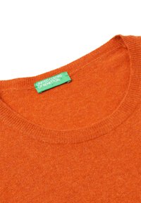 Pomarańczowy sweter dzianinowy z okrągłym dekoltem. Zawiera zieloną metkę z napisem "UNITED COLORS OF BENETTON" na wewnętrznej stronie kołnierza. Miękka struktura.
