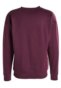 Felpa a maniche lunghe con collo tondo in un intenso color bordeaux, mostrata dal retro con polsini e orlo a costine.
