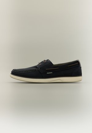 Czarny skórzany but typu boat shoe z białą podeszwą, brązowymi sznurowadłami i logo Barbour po boku, pokazany z profilu na neutralnym tle.