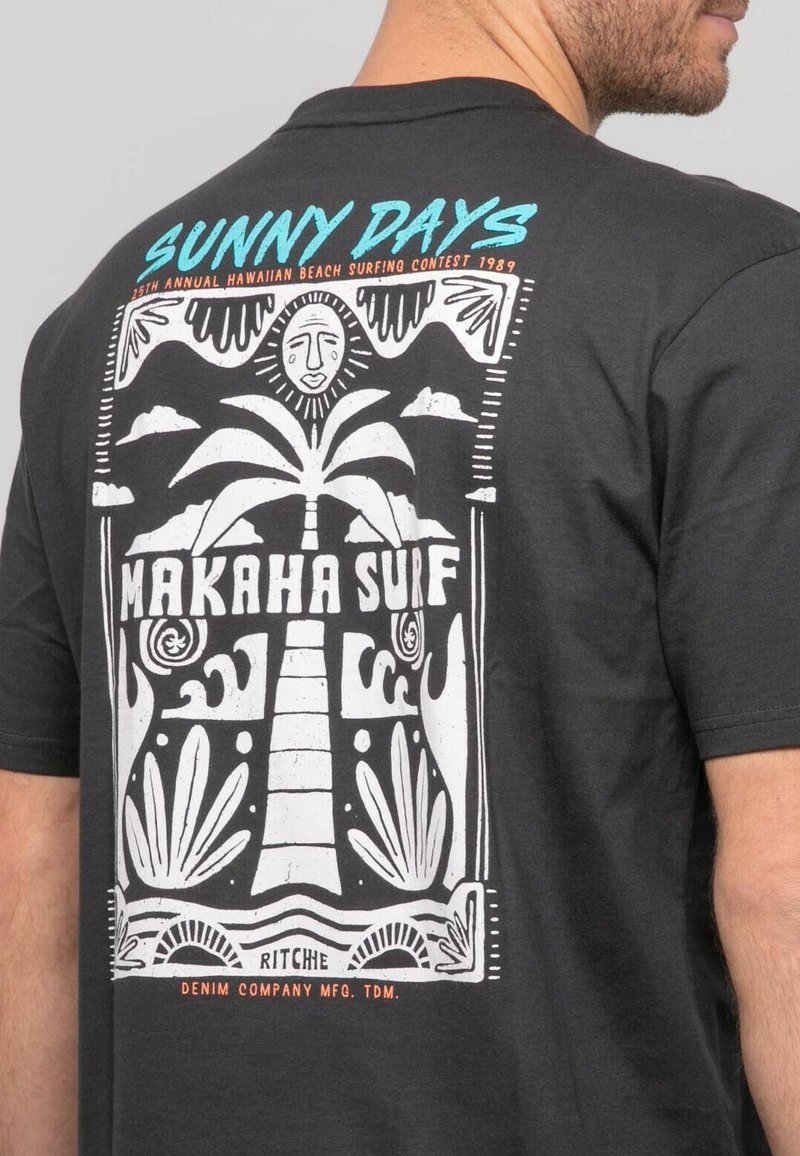 T-shirt noire à manches courtes avec un imprimé graphique blanc représentant un palmier, un soleil et des vagues, accompagné d'un texte turquoise et orange : "JOURS ENSOLEILLÉS" et "MAKAHA SURF."