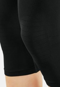 Black compression shorts with textured ribbing patterns. Fitted design with a smooth texture, extending to mid-thigh length.