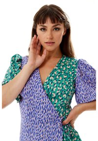 Wrap dress featuring a v-neckline, puff sleeves, and a mix of blue and green patterns with pink accents. Made from a lightweight fabric.