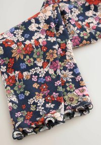 Tessuto con motivo floreale in blu scuro, con fiori rossi, rosa e verdi. Texture morbida con bordi ondulati e arricciati.