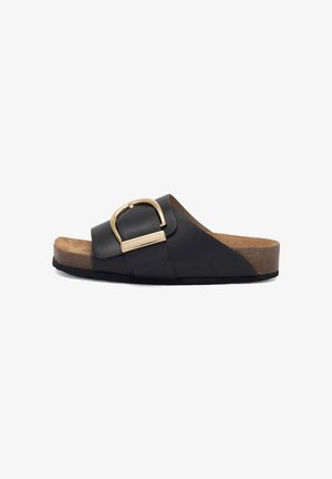 Czarna skórzana klapka z szerokim paskiem ozdobionym złotą metalową klamrą. Korekowa wkładka i teksturowana gumowa podeszwa zapewniające wsparcie.