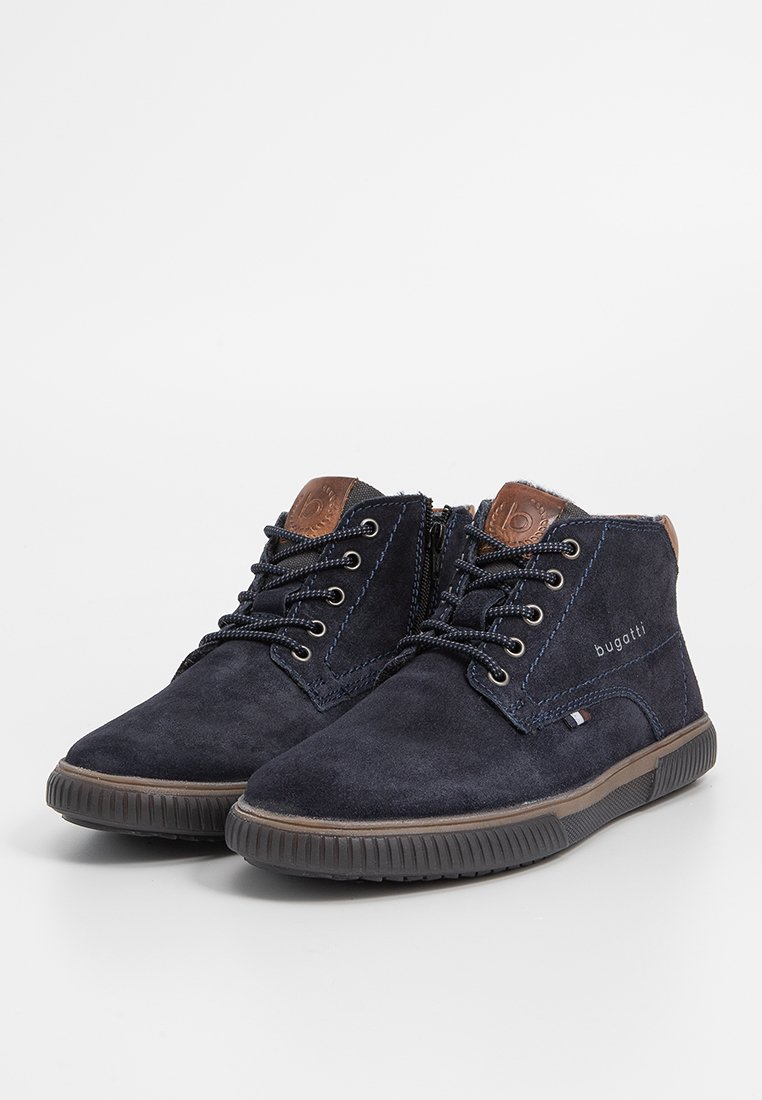 Botas de ante azul marino hasta el tobillo con detalles en cuero marrón, diseño con cordones, cremallera lateral y una suela de goma texturizada para mayor agarre.