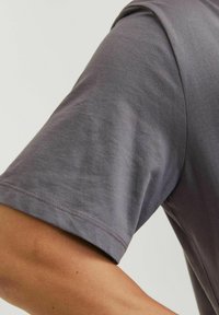 Korte mouwen shirt in gedempt grijs stof met een gladde textuur, ronde halslijn en zichtbare stiksels langs de randen.