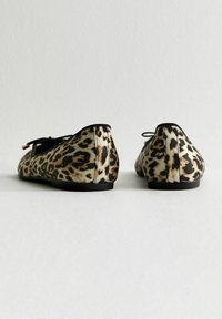 Leopard print flat shoes with black trim, satin-like finish, rounded toe, and lace detail. Smooth texture and low-profile sole.