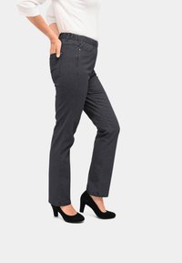 Grijze broek met een textuur, voorzien van zijzakken en een tailleband, gecombineerd met zwarte hoge hakken.