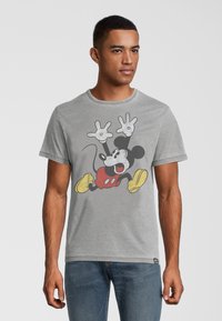 Harmaa lyhythihainen t-paita, jossa on suuri kuva Mikki Hiirestä punaisissa shortseissa ja keltaisissa kengissä, merkittävillä mustilla ja valkoisilla yksityiskohdilla.