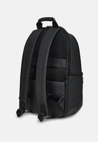 Mochila negra con un diseño elegante, paneles de malla texturizada, correas de hombro acolchadas y compartimentos con cremallera para almacenamiento.