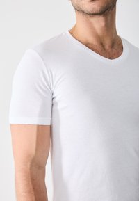 White cotton t-shirt with a V-neck design, short sleeves, and a smooth, lightweight texture. No visible patterns or graphics.