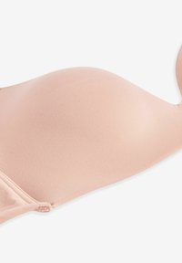 Soutien-gorge rembourré rose clair avec une texture lisse, bretelles ajustables et armature superposée pour un soutien. Tissu doux recouvre les bonnets.