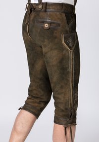 Braune Lederhosen aus Leder, mit einem Reißverschlussfach, dekorativer Stickerei und umgeschlagenen Säumen, die mit Bändern gesichert sind.