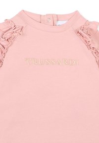 Haut en coton rose clair avec des accents froncés sur les épaules et un logo "TRUSSARDI" brodé dans une teinte plus claire. Fermeture à boutons au dos.