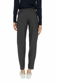 Pantalones de cuadros en blanco y negro ajustados con pierna tapered, cintura elástica y bolsillos laterales. Llevados con zapatillas blancas.