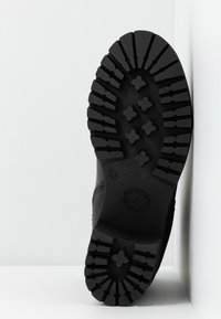 Černá podrážka bot s hlubokým, agresivním vzorem pro trakci, s texturovaným povrchem a gumovou konstrukcí. Velikost označena jako 37.