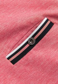 Rød meleret stof har en lille påsyet lomme med lukning med fire knapper og en stribet detalje i sort, hvid og pink.