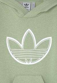 Mintgrön hoodie med en stor vit Adidas trefoil-logotyp på framsidan. Tyget har en mjuk textur och har en känguruficka längst ner.