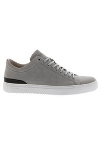 Zapatilla de gamuza gris con suela de goma blanca, puntera redondeada, seis ojales y un acento negro en el talón. Diseño minimalista con textura suave.