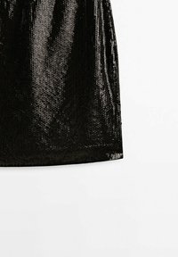 Jupe noire à sequins avec un design ajusté, une texture lisse et une surface scintillante, se rétrécissant vers un ourlet droit.