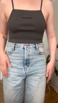 Grå ribbet tanktop med tynde stropper, featuring et frontlogo. Båret med lyseblå højtaljede jeans med et falmet look.