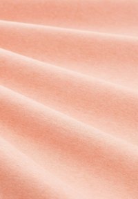 Miękka, teksturowana tkanina w jasnym brzoskwiniowym kolorze z subtelnym połyskiem, charakteryzująca się gładkimi fałdami i jednolitym wzorem tkanym.