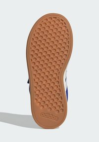 Adidas-sko sula med ett hexagonalt texturmönster. Färgen är beige med brunt gummi. Innehåller varumärkeslogotypen nära hälen.