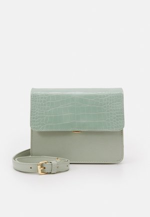 Sac bandoulière en faux cuir vert avec un motif crocodile texturé sur le rabat, ferrures dorées et une sangle ajustable.