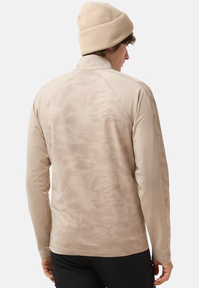 Beige long-sleeve top with a subtle camouflage pattern, high collar, and raglan sleeves; paired with a matching beige knit beanie.