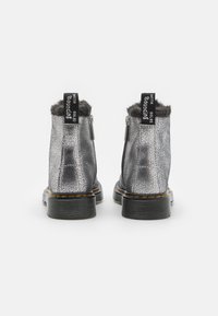 Zilveren, textuurvolle enkellaarsjes met een nep-bonten rand, zijritsen en zwarte rubberen zolen met gele stiksels accenten.