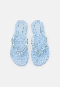 Infradito di colore azzurro chiaro con suole intrecciate a trama. Presentano fasce trasparenti decorate con gemme disposte a forma di V. Design piatto.