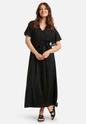 Schwarzes Maxikleid mit V-Ausschnitt, kurzen schwingenden Ärmeln und einem Bindegürtel in der Taille. Glattes Material und fließendes Design. Getragen mit schwarzen Sandalen.
