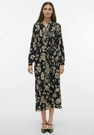 Robe longue noire avec un motif floral crème, col, manches longues, taille cintrée avec lien, et longueur mi-mollet fluide.