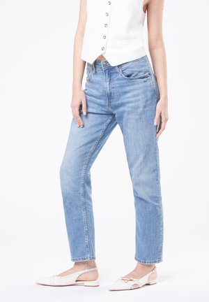 Jeans in denim leggero azzurro con una vestibilità a gamba dritta, caratterizzati da un alto punto vita e un leggero effetto invecchiato. Abbinati a scarpe bianche senza lacci.