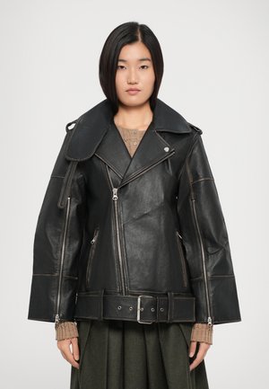 Black leather biker jacket with oversized collar, metallic zippers, side pockets, and a fitted belt. Textured finish with contrasting stitching.