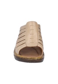 Beige leren slipper met open teen, voorzien van verticale banden en gestikte accenten. Getextureerde zool met geweven details.
