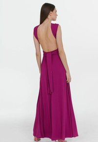 Dlouhé, hluboké šaty s fuchsiovou látkou. Mají bezrukávový design, látkový pás v oblasti pasu a splývavou sukni. Hladká textura.