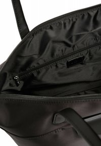 Zwarte tote bag interieur met een gladde stofvoering, een ritsvak en logo-detail; voorzien van twee stevige handgrepen en een ritssluiting.
