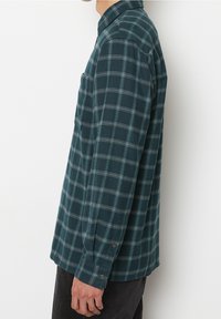Zielona koszula flanelowa w kratę z kołnierzykiem na guziki, długimi rękawami i kieszenią na piersi. Wzór zawiera kontrastujące jasnoniebieskie linie.