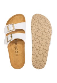 Des sandales blanches à glisser avec deux sangles réglables et des boucles dorées, présentant une semelle intérieure en suede marron doux et une semelle extérieure en caoutchouc beige texturé.
